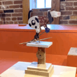 Moving wooden sculpture of dog skiing.